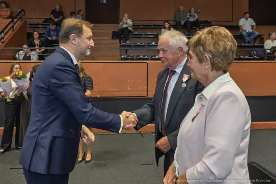 Wręczenie odznaczeń w trakcie uroczystości, uściski dłoni i gratulacje.