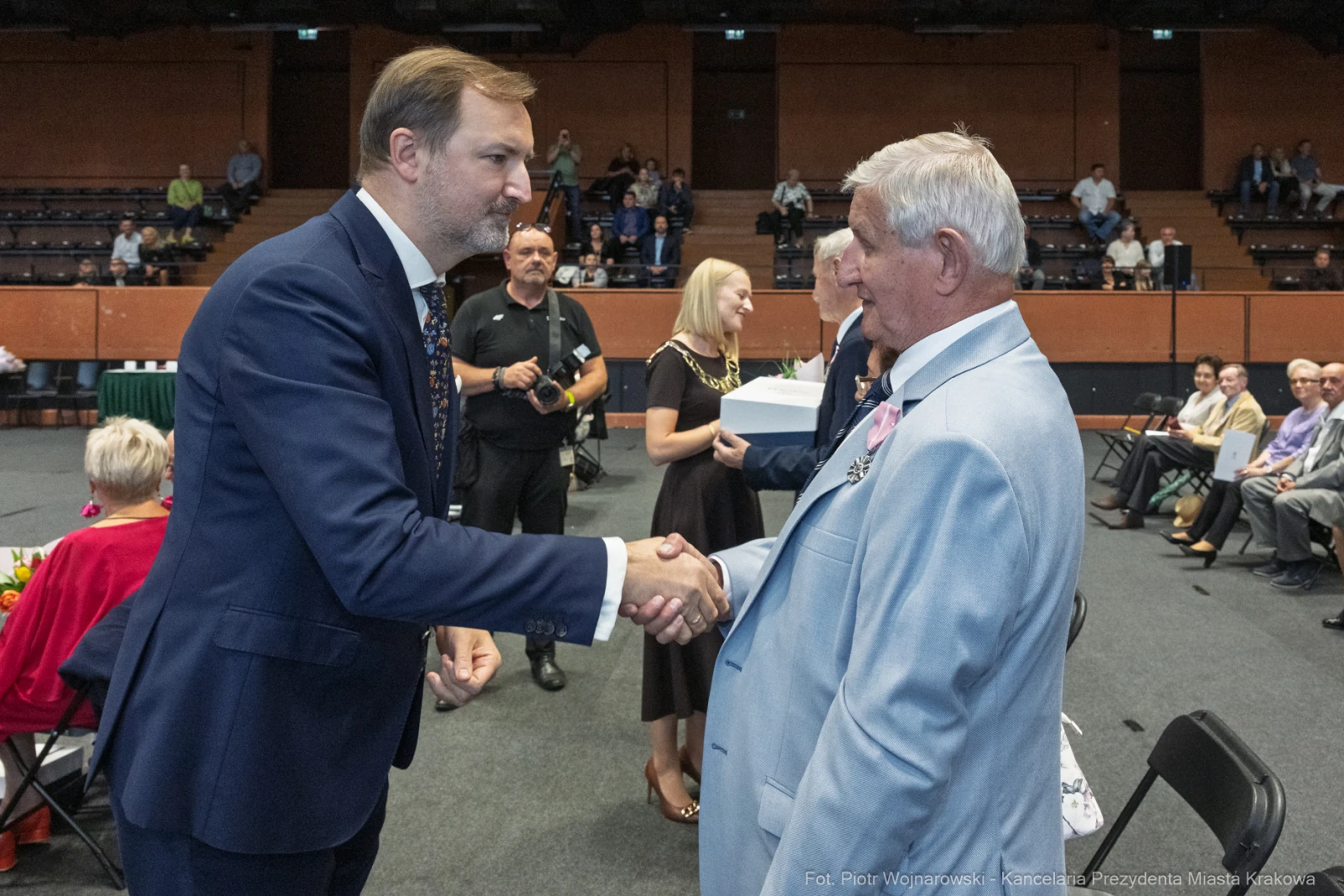 Mężczyźni uściskiem dłoni składają sobie gratulacje podczas uroczystości.  Autor: Piotr Wojnarowski