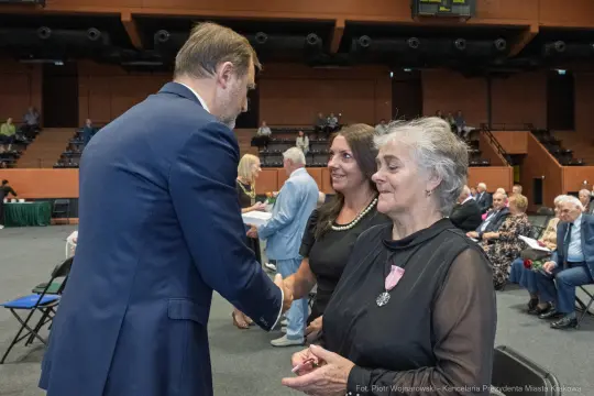 Uroczystość wręczenia odznaczeń, uściski dłoni i uśmiechy uczestników.