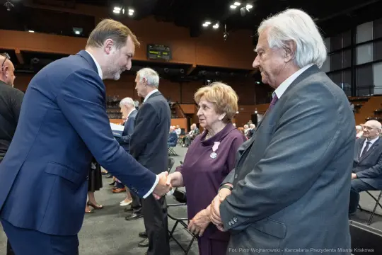 Uroczystość wręczenia odznaczeń, uściski dłoni i rozmowy między uczestnikami.