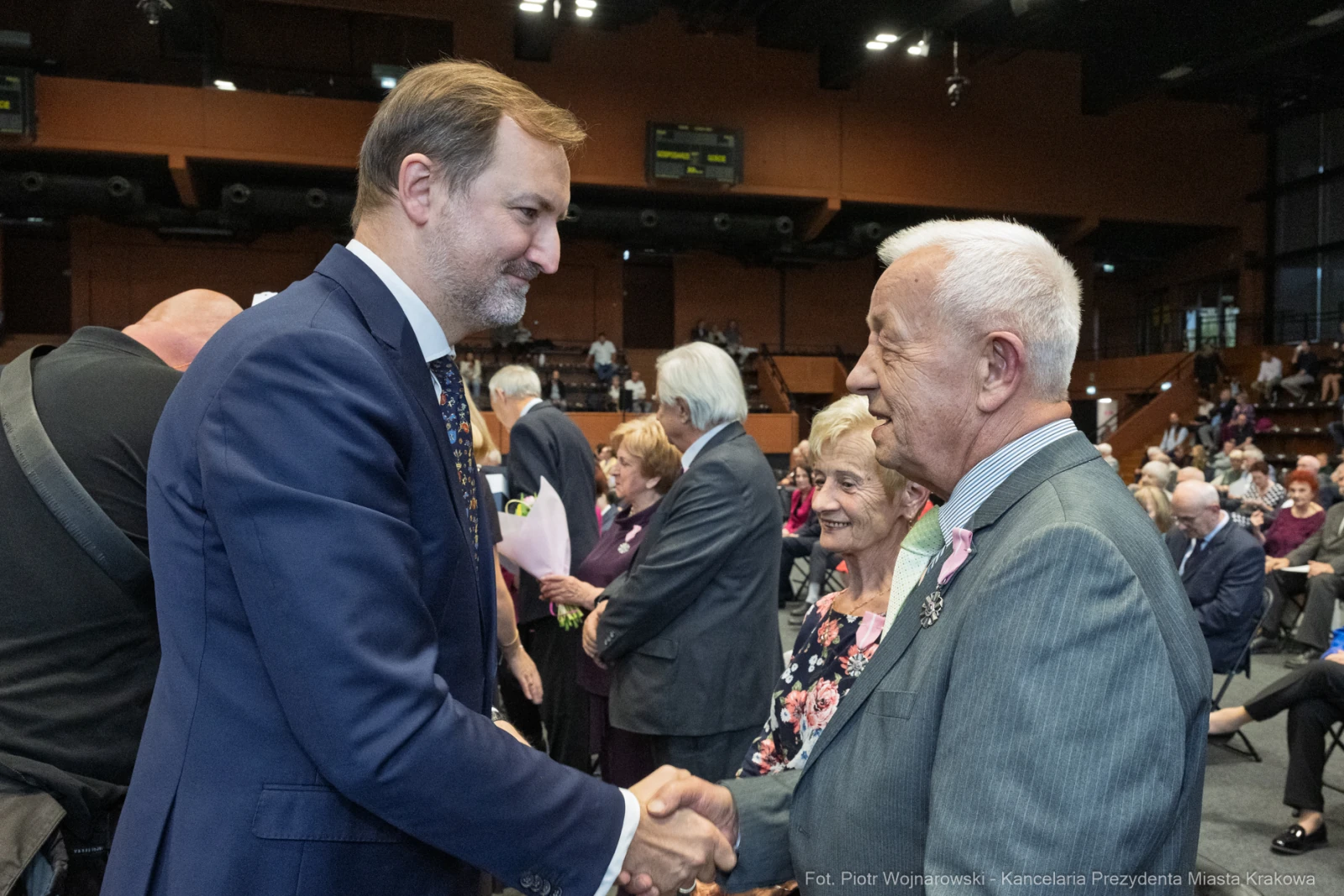 Spotkanie dwóch mężczyzn, jeden z nich uścisnął dłoń drugiego, w tle starsi ludzie.  Autor: Piotr Wojnarowski