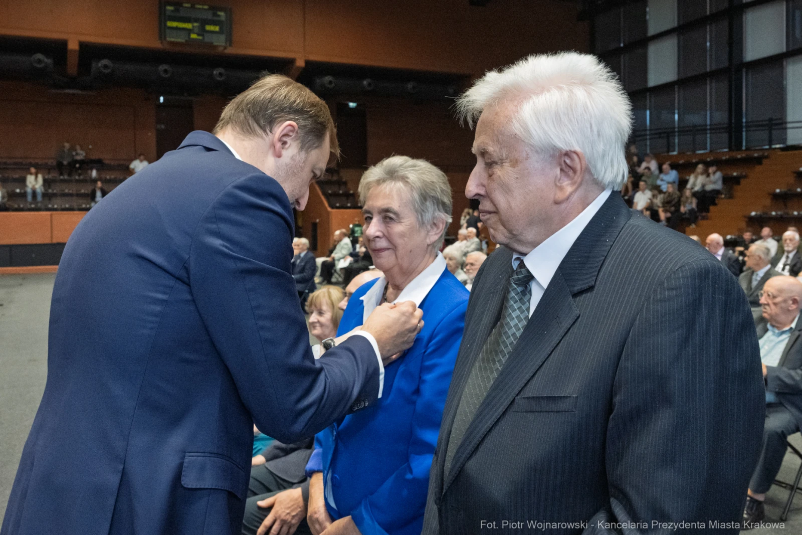 Wręczenie odznaczenia przez mężczyznę starszej parze w sali pełnej ludzi.  Autor: Piotr Wojnarowski