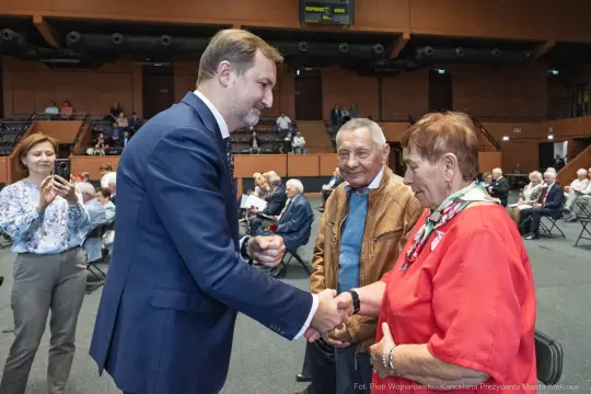 Spotkanie polityka z seniorami, uściski dłoni i rozmowy.