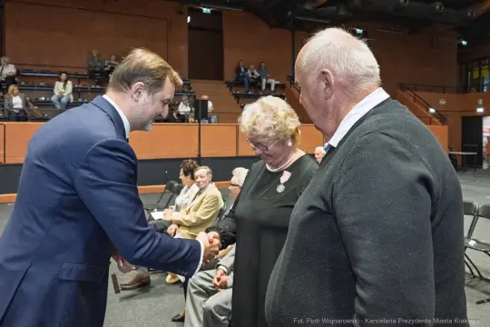 Spotkanie trzech osób, w tym mężczyzny w garniturze i starszej pary.