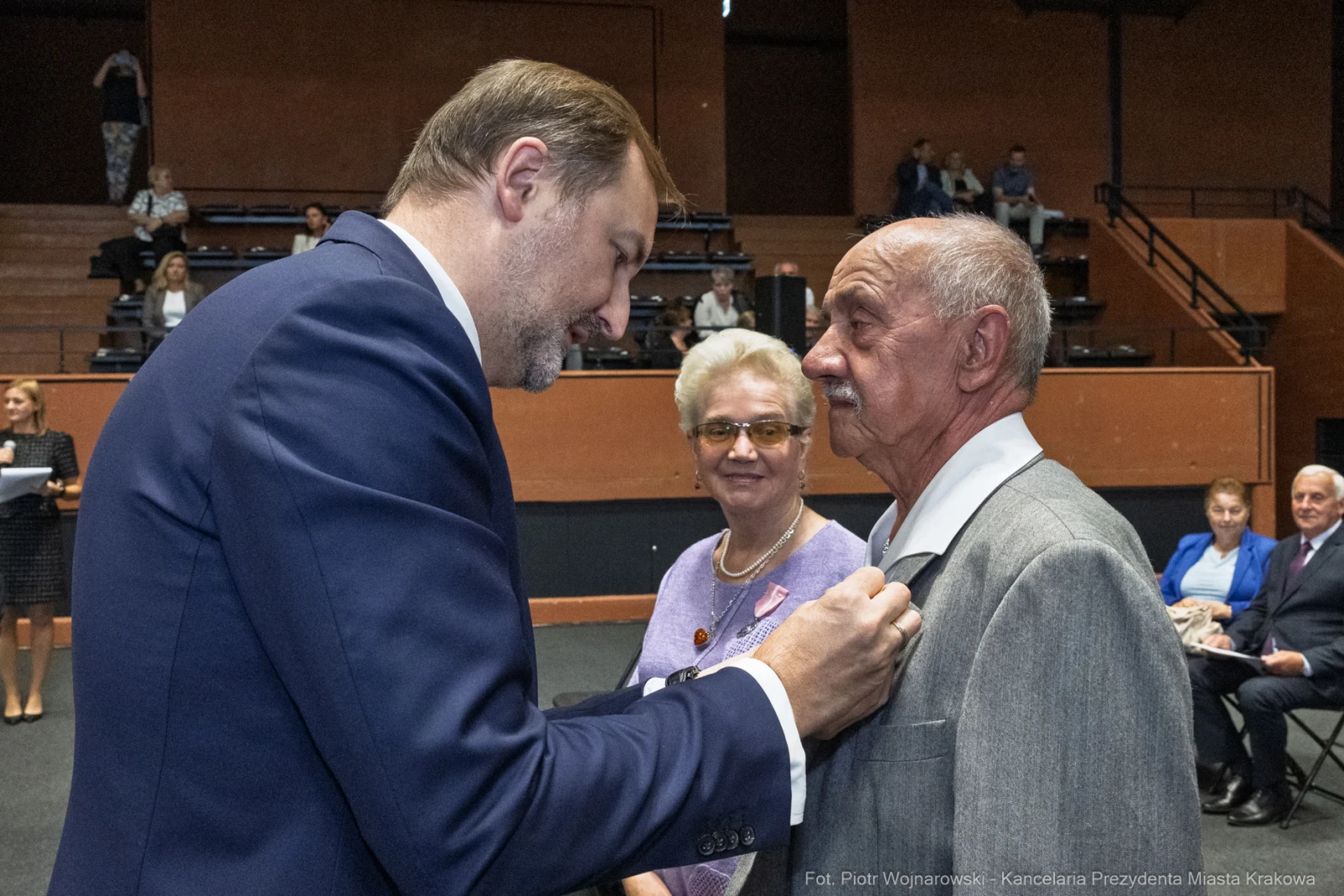 Wręczenie odznaczenia mężczyźnie przez innego mężczyznę, w tle widoczni goście.  Autor: Piotr Wojnarowski