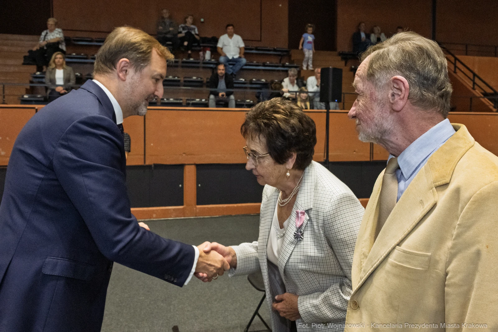 Spotkanie trzech osób, w tym mężczyzny w garniturze i dwóch starszych ludzi, w trakcie uścisku dłoni.  Autor: Piotr Wojnarowski