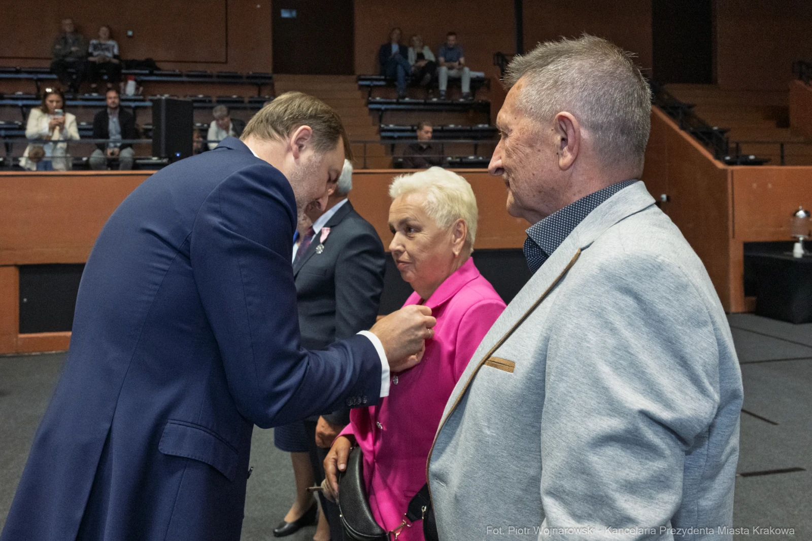 Wręczenie odznaczeń w sali obrad, uczestnicy w formalnych strojach.  Autor: Piotr Wojnarowski