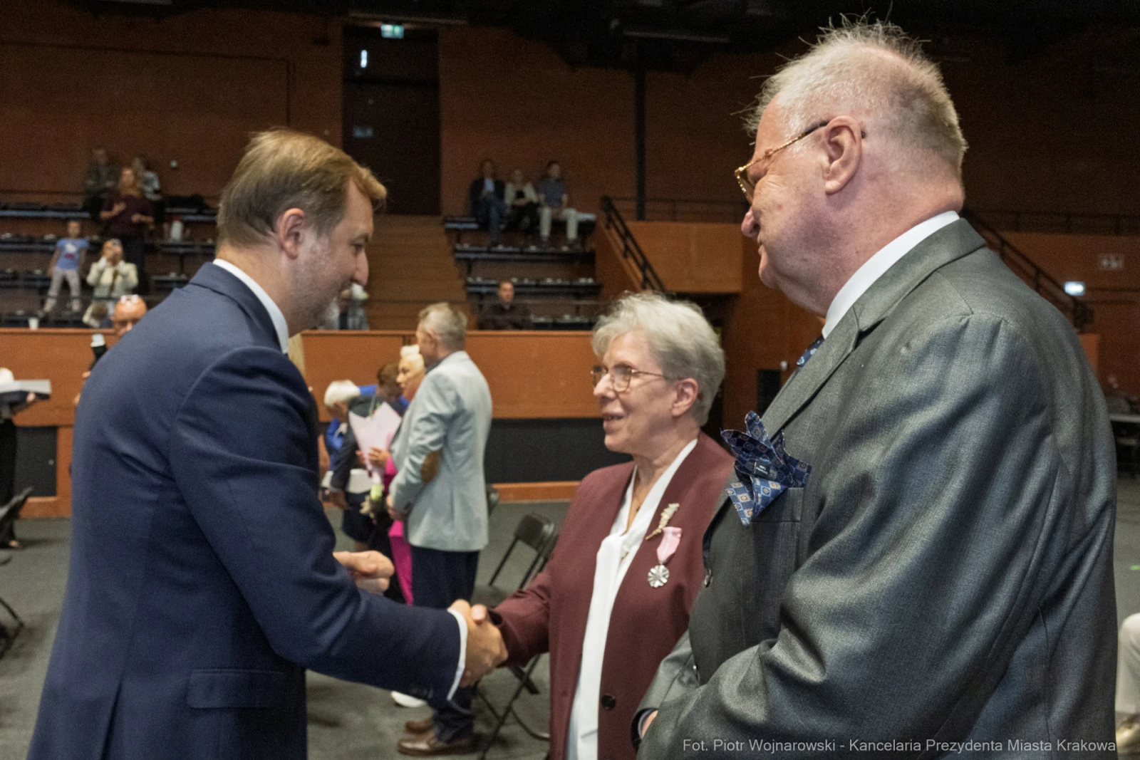 Spotkanie trzech osób, jedna z nich w garniturze, uściski dłoni i rozmowy.  Autor: Piotr Wojnarowski