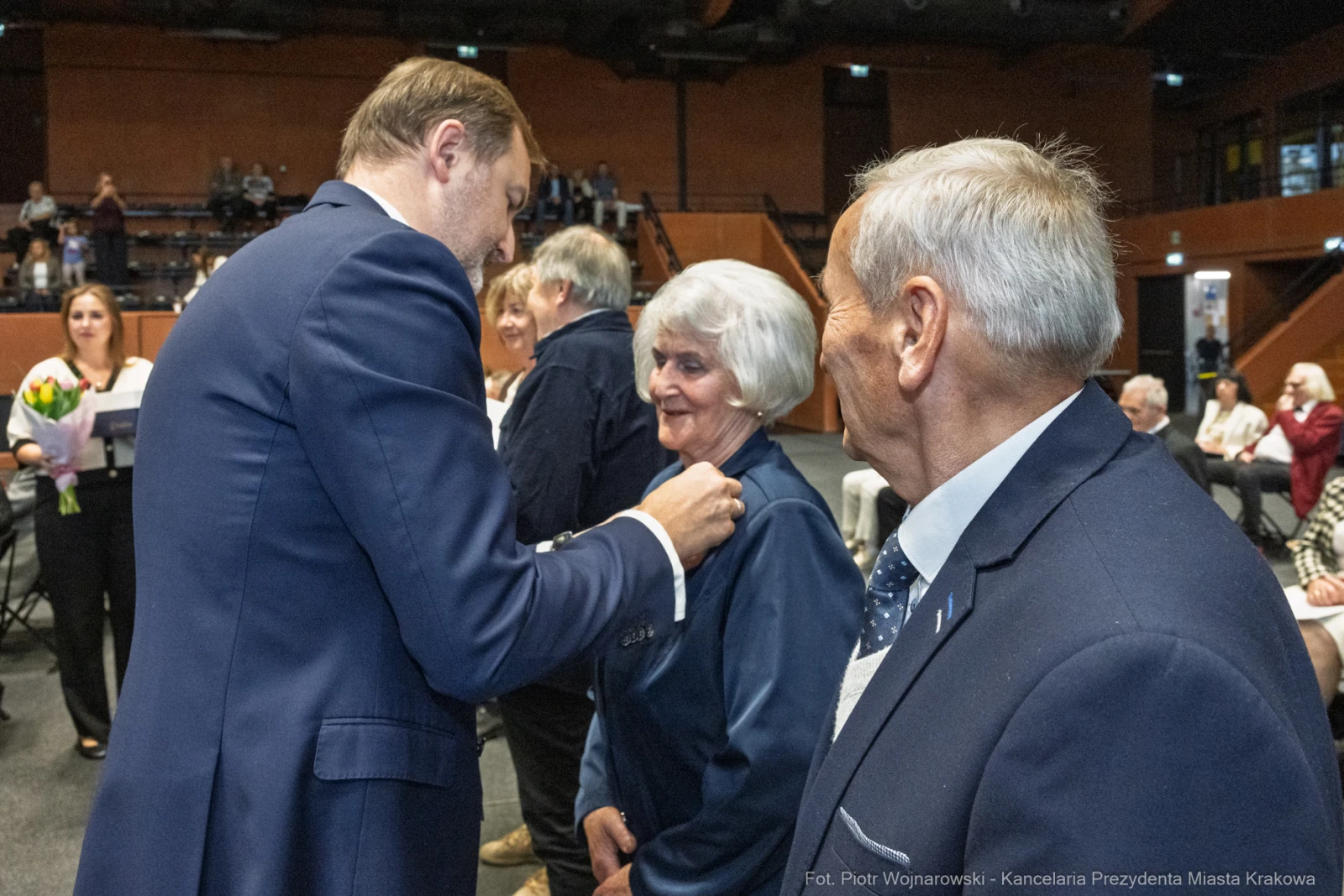 Uroczystość wręczenia odznaczeń, osoby w eleganckich strojach, uśmiechy i gratulacje.  Autor: Piotr Wojnarowski