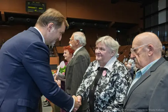 Uroczystość wręczenia nagród, uściski dłoni i uśmiechy uczestników.