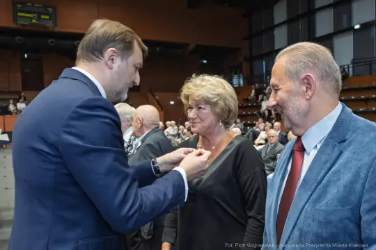 Wręczenie odznaczenia przez mężczyznę kobiecie w towarzystwie drugiego mężczyzny.