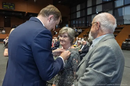 Wręczenie odznaczenia kobiecie podczas uroczystości w sali.