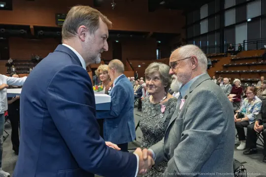 Uroczystość wręczenia nagród, uściski dłoni i uśmiechy uczestników.