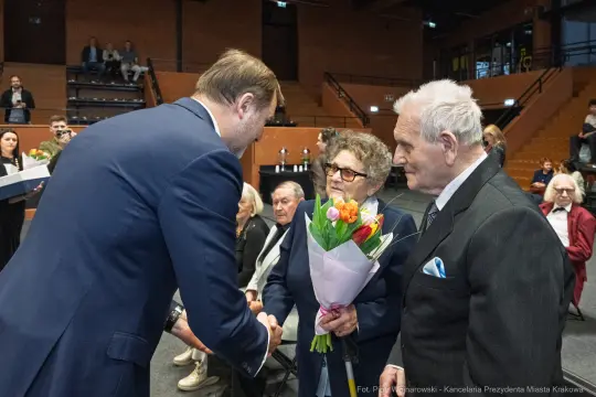 Wręczenie kwiatów starszej parze podczas uroczystości.