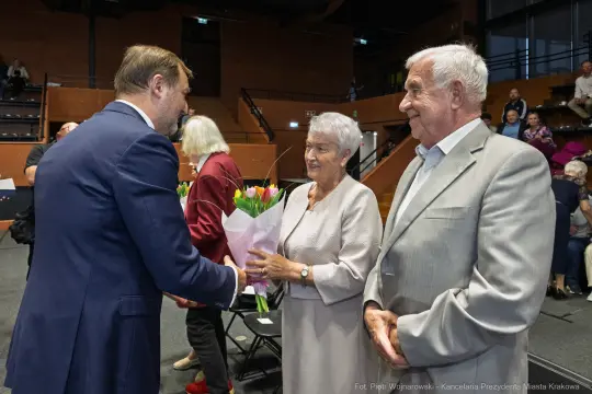 Uroczystość wręczenia kwiatów starszej parze.
