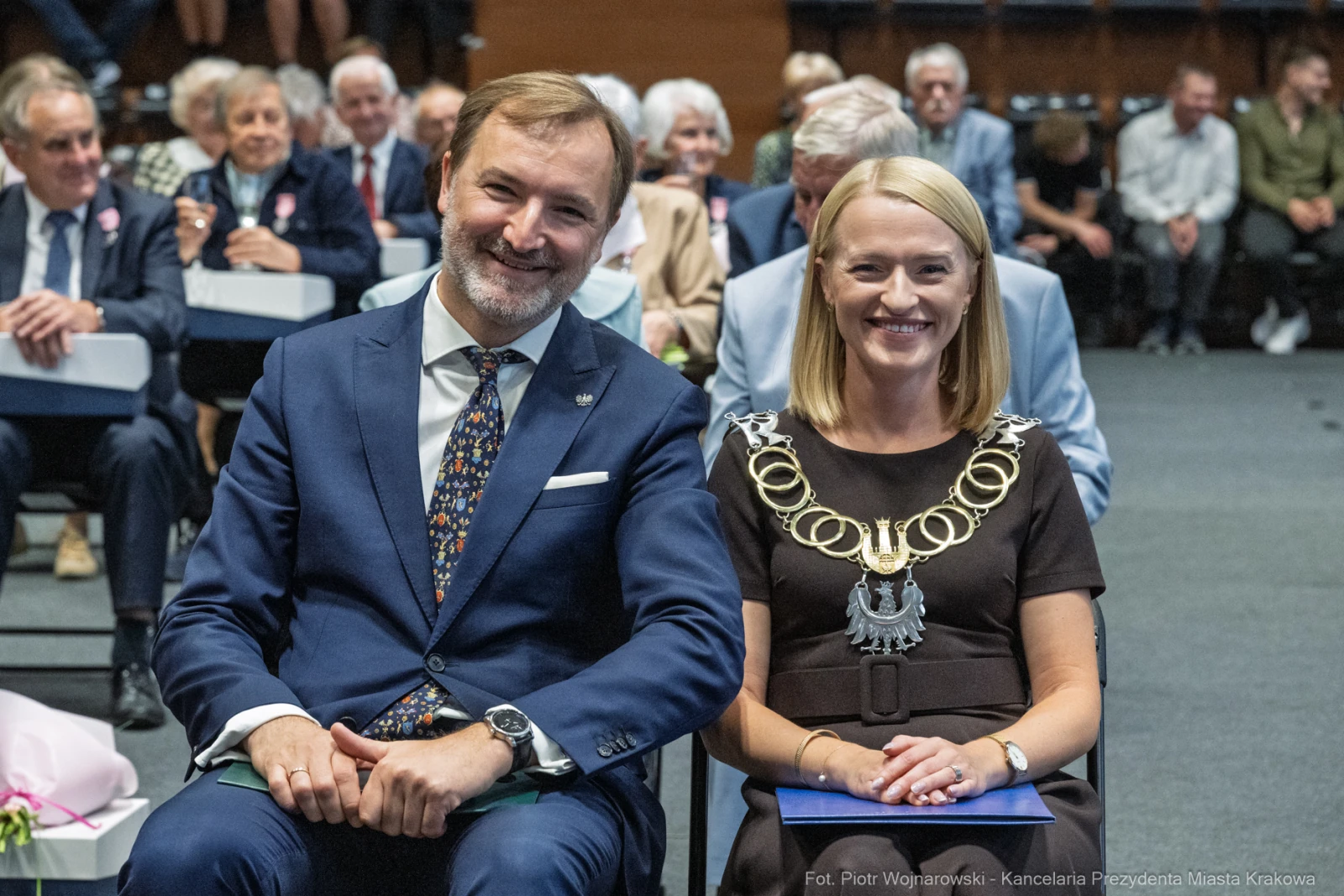 Uśmiechnięci mężczyzna i kobieta w eleganckich strojach, siedzący na wydarzeniu.  Autor: Piotr Wojnarowski
