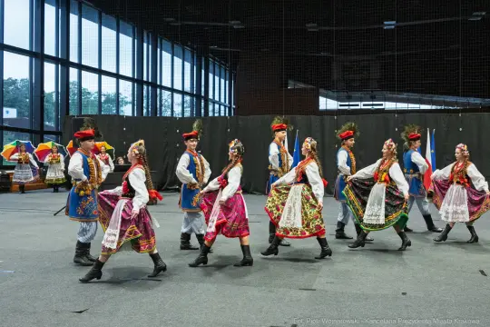 Tancerze w tradycyjnych strojach ludowych wykonują taniec.