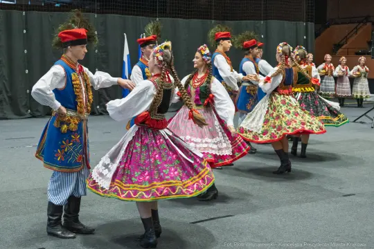 Grupa tancerzy w tradycyjnych strojach ludowych tańczy w rytm muzyki.