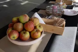 Stos jabłek na talerzu obok akcesoriów do serwowania.