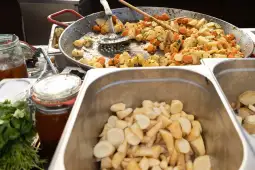 Warzywa duszone w dużym garnku obok pokrojonych warzyw w pojemniku.