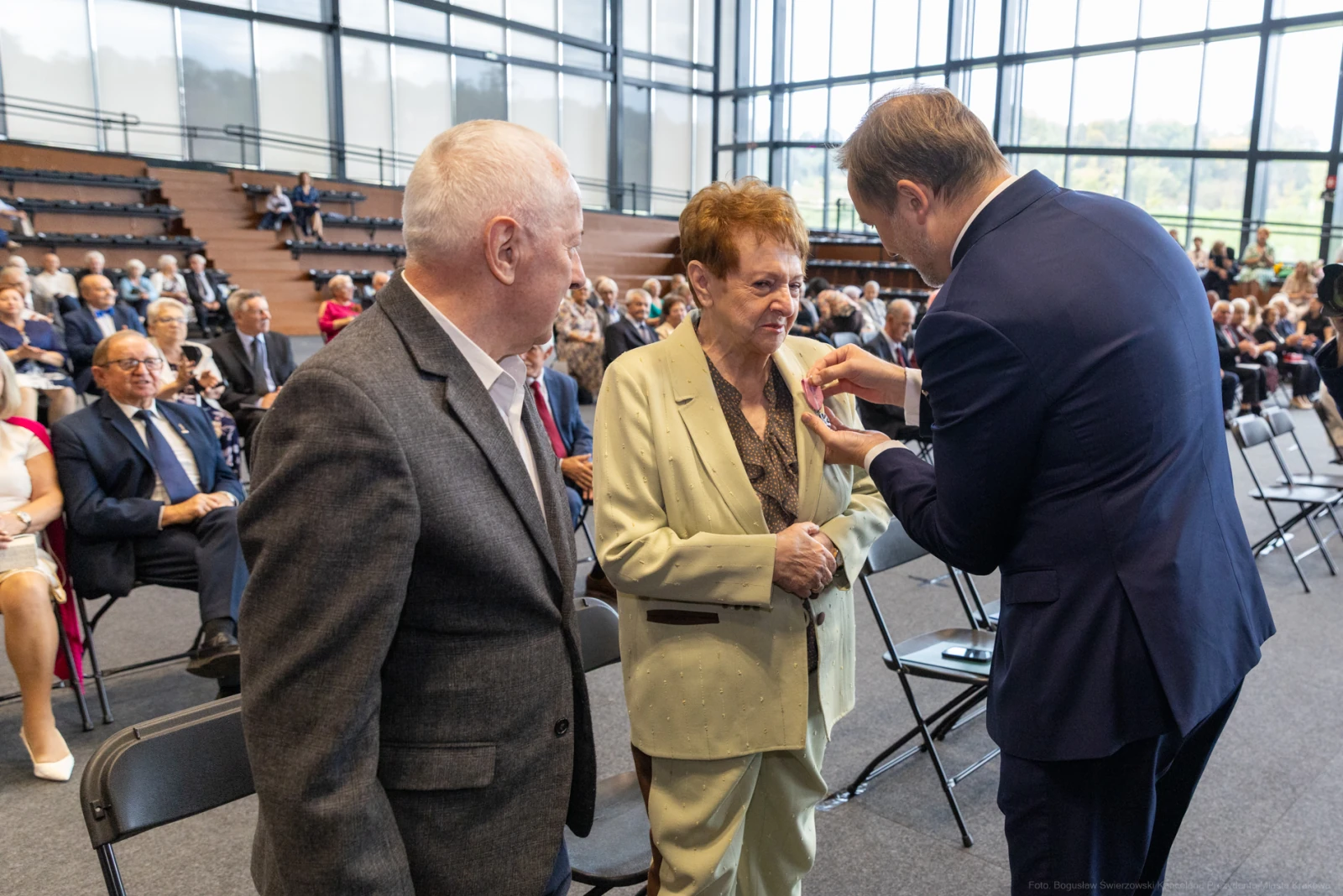 Uroczystość wręczenia odznaczeń, starsza kobieta odbiera medal od mężczyzny. W tle zgromadzenie gości.  Autor: Bogusław Świerzowski