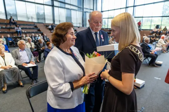 Uroczystość wręczenia kwiatów i odznaczeń w sali z widownią.