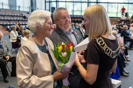 Uroczystość wręczenia kwiatów parze seniorów.