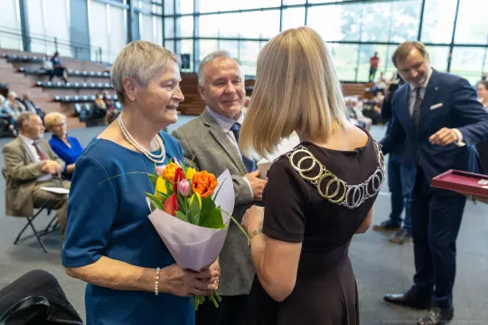 Uroczystość wręczenia kwiatów i nagród, uczestnicy w formalnych strojach.