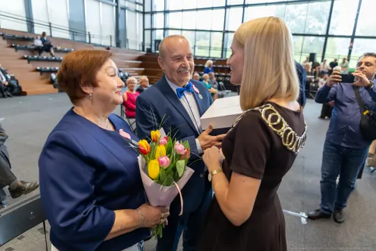 Wręczenie nagrody z okazji jubileuszu, kwiaty i uśmiechy uczestników.