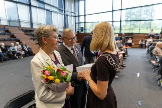 Uroczystość wręczenia kwiatów i gratulacji w sali z widownią.
