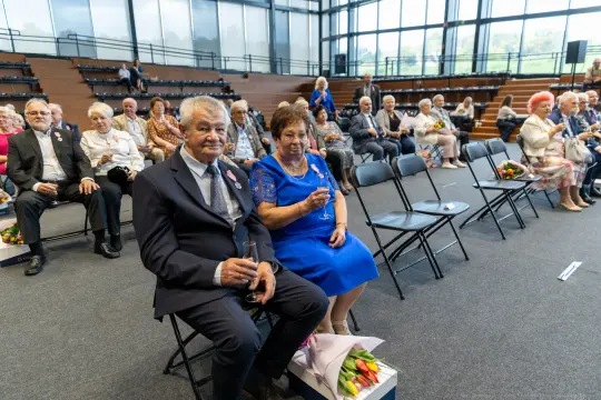 Para siedząca na widowni, otoczona przez innych uczestników wydarzenia.