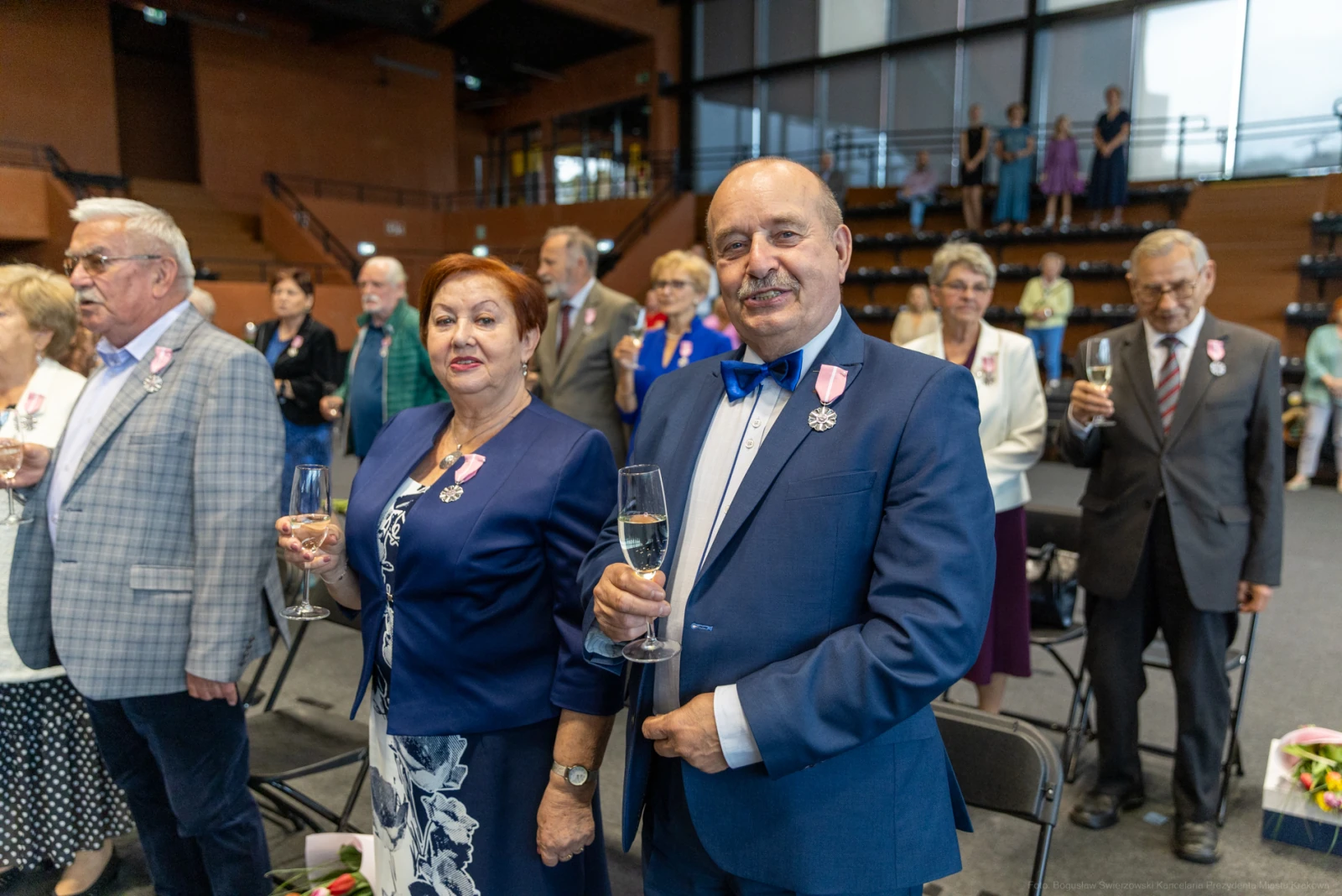 Uroczystość z udziałem osób w eleganckich strojach, trzymających kieliszki.  Autor: Bogusław Świerzowski