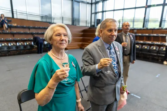 Para osób w eleganckich strojach trzyma kieliszki, celebrując wyjątkowy moment.