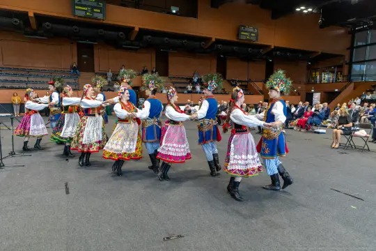 Grupa tancerzy w tradycyjnych strojach ludowych tańczy w rytm muzyki.