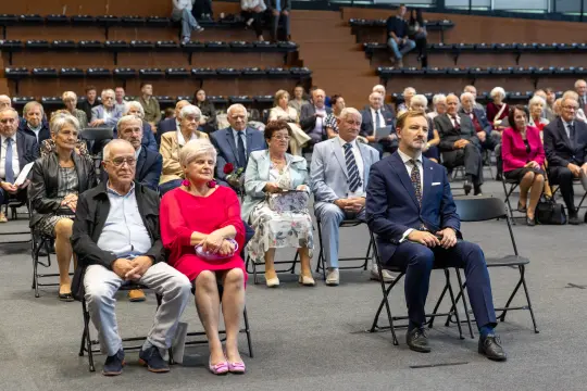 Grupa osób siedzących na widowni podczas uroczystości.