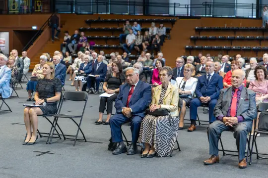 Grupa ludzi siedzących na widowni podczas wydarzenia.