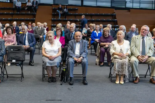 Grupa starszych osób siedzących na widowni podczas wydarzenia.