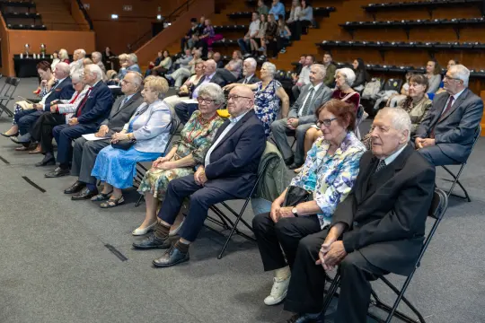 Grupa starszych osób siedzących na widowni podczas wydarzenia.