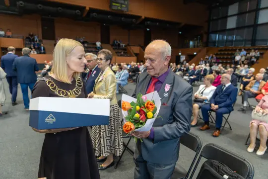 Wręczenie kwiatów i nagrody podczas uroczystości w sali konferencyjnej.