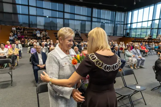 Uroczystość wręczenia kwiatów w sali z publicznością.