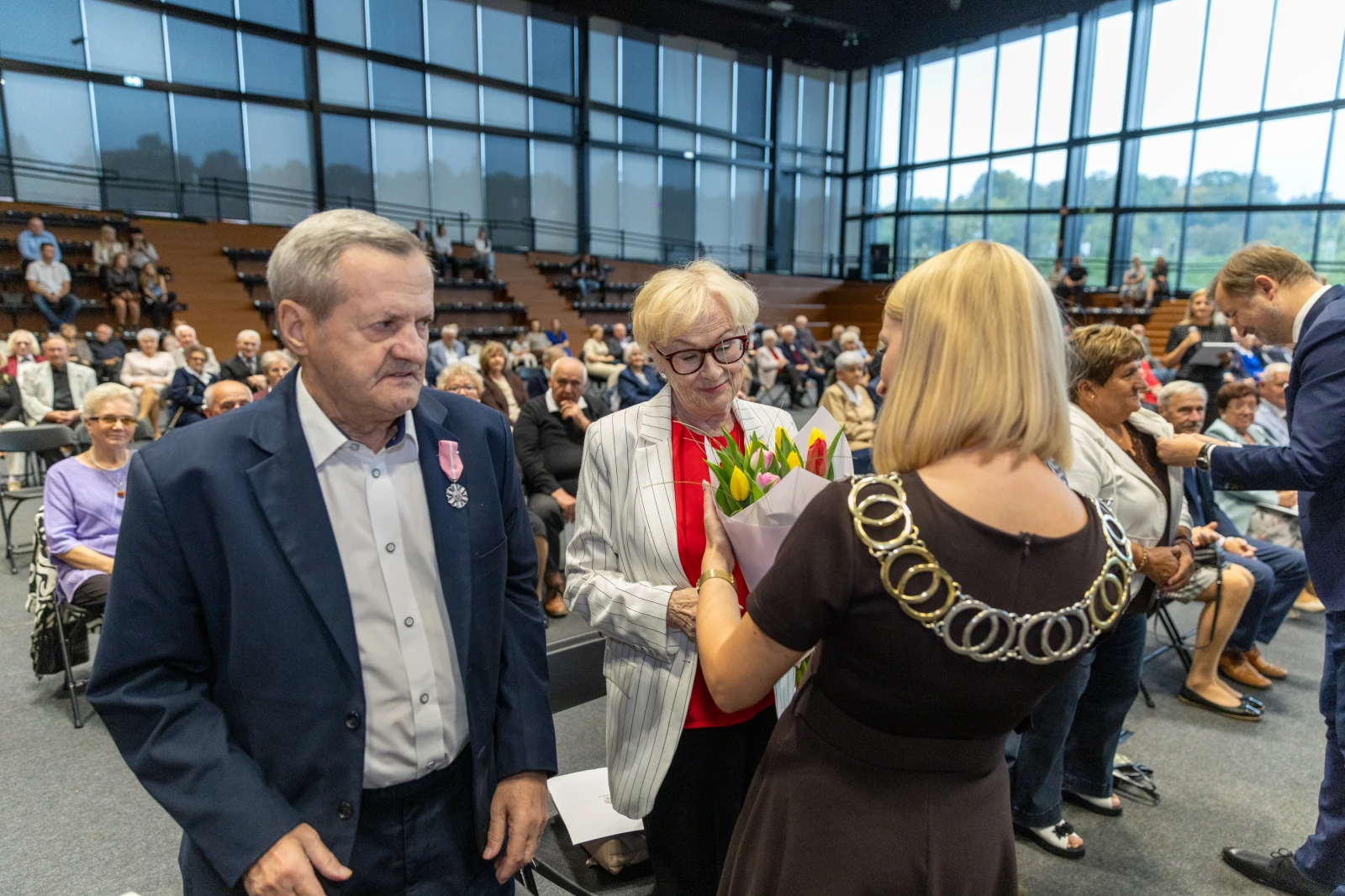 Uroczystość wręczenia nagród z kwiatami i odznaczeniami w tle zgromadzeni goście.  Autor: Bogusław Świerzowski