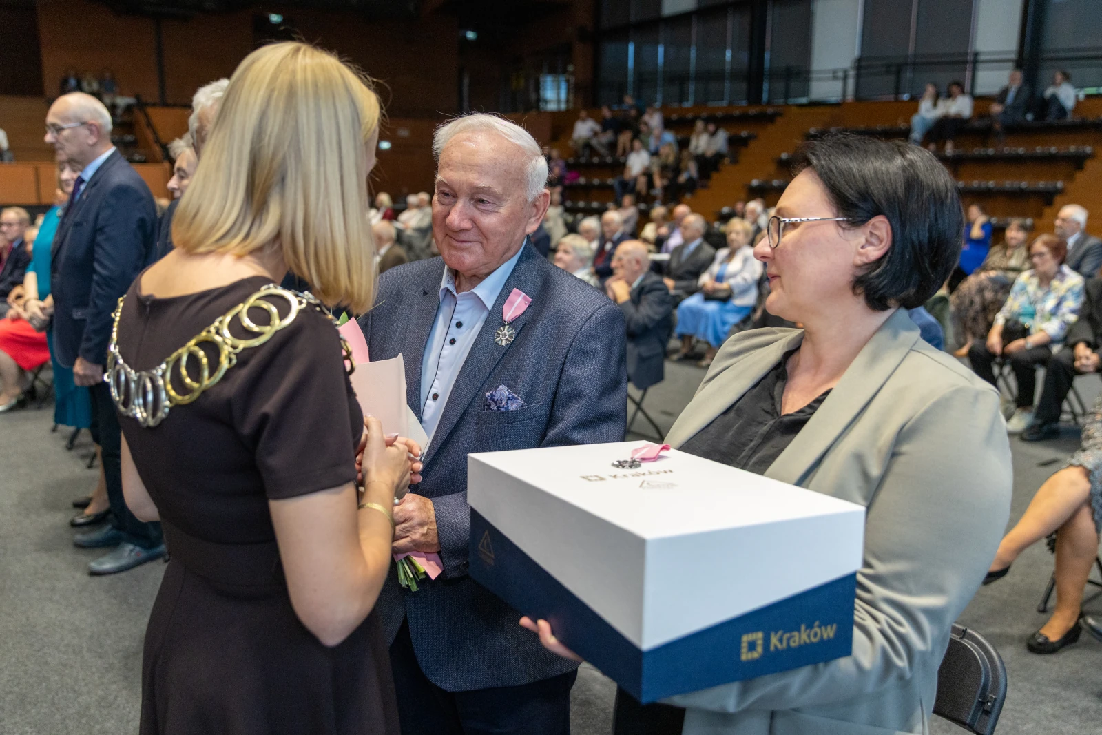 Uroczystość wręczenia odznaczeń w Krakowie. Osoby w formalnych strojach, kwiaty i upominki.  Autor: Bogusław Świerzowski
