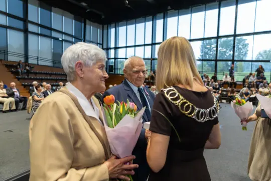 Uroczystość wręczenia kwiatów i gratulacji dla starszych osób.