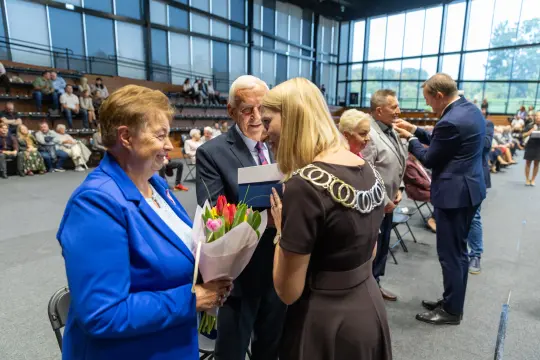 Uroczystość wręczenia nagród z kwiatami i uśmiechami uczestników.