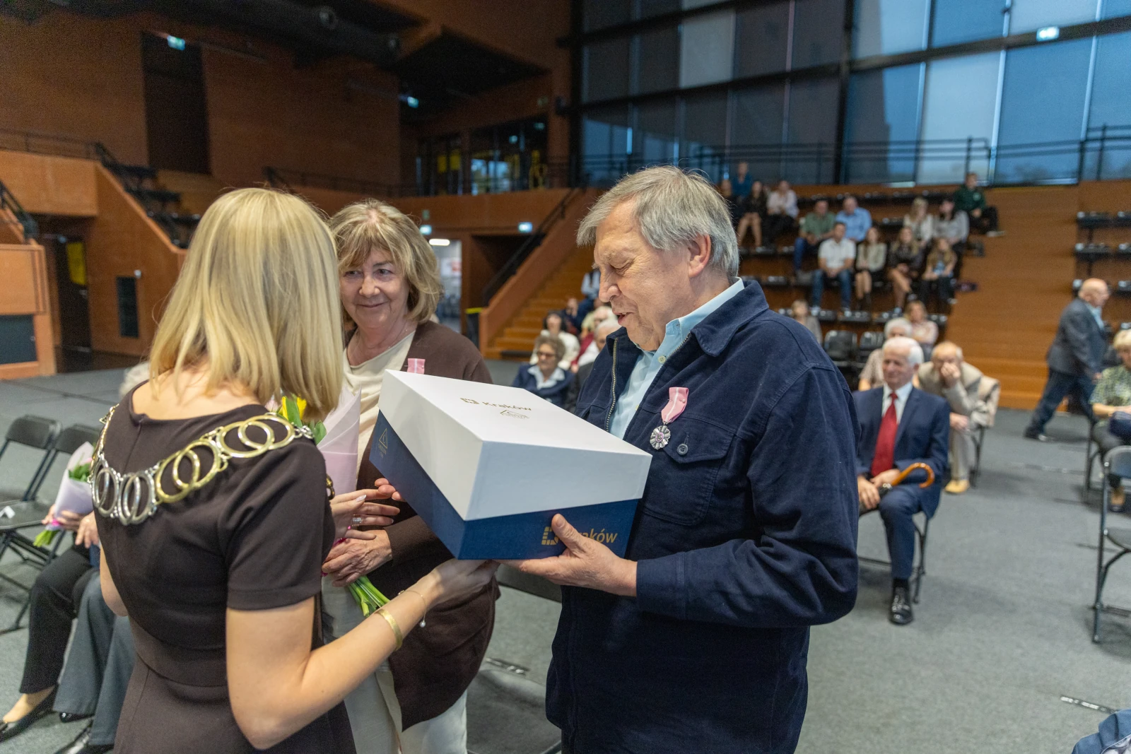Wręczenie nagrody mężczyźnie przez dwie kobiety w sali pełnej widzów.  Autor: Bogusław Świerzowski