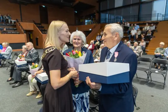 Uroczystość wręczenia nagród z kwiatami i prezentami dla wyróżnionych osób.