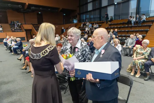 Uroczystość wręczenia nagród z kwiatami i prezentami dla wyróżnionych osób.