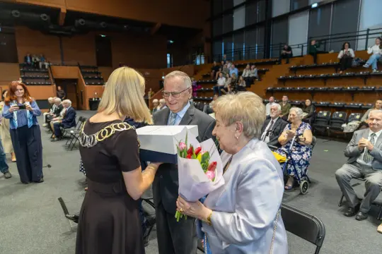 Uroczystość wręczenia nagrody z bukietem kwiatów i prezentem.