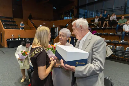 Uroczystość wręczenia nagród, jubilaci otrzymują kwiaty i upominki.