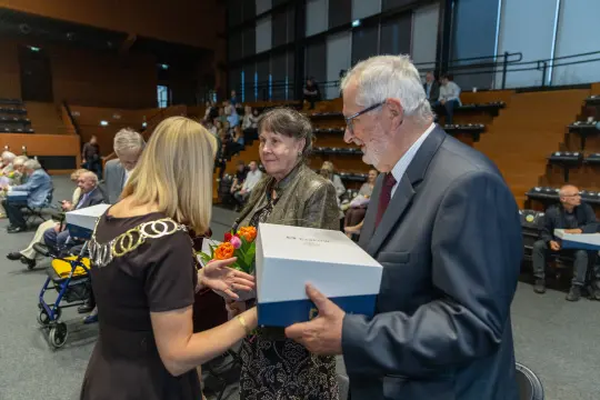 Wręczenie nagród podczas uroczystości, osoby z kwiatami i prezentami.